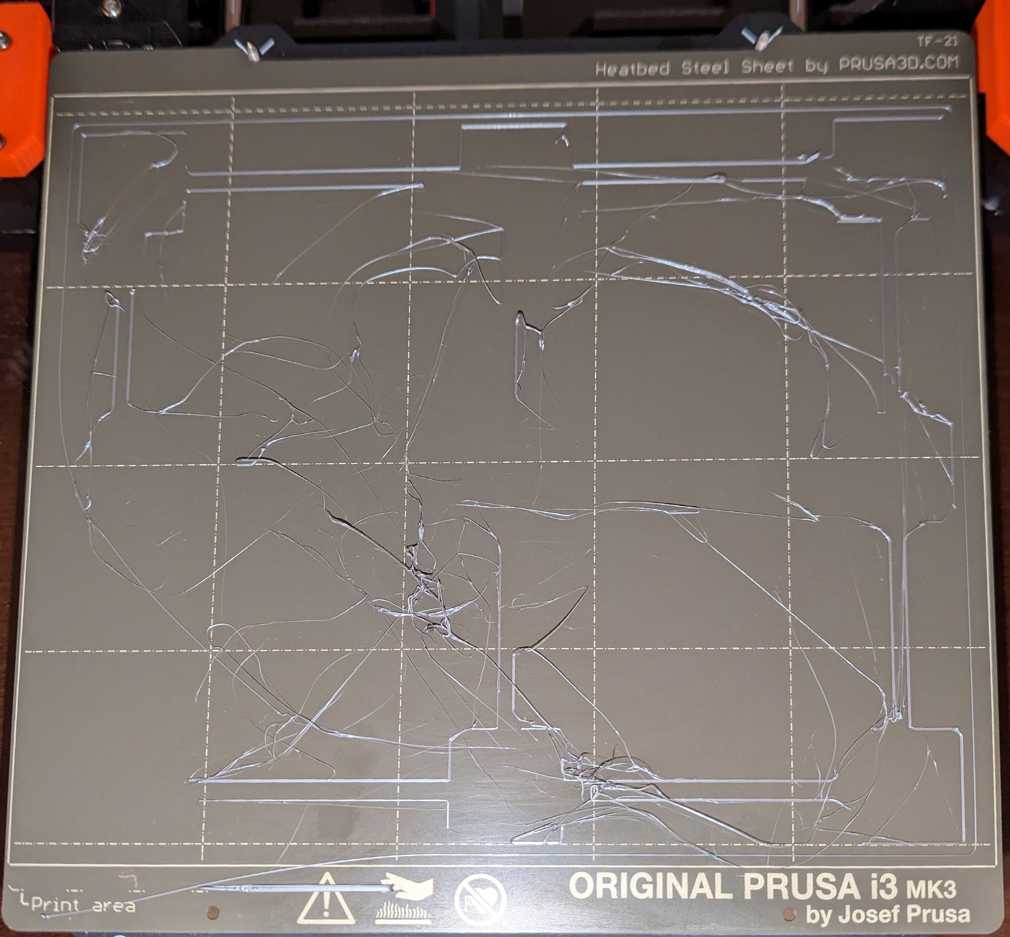 Prusa bed leveling test failure that looks like the Z height is too high and has stringing everywhere from poor bed adhesion.